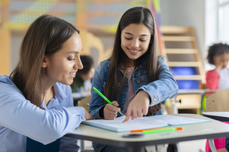 Teacher helping girl in classroom